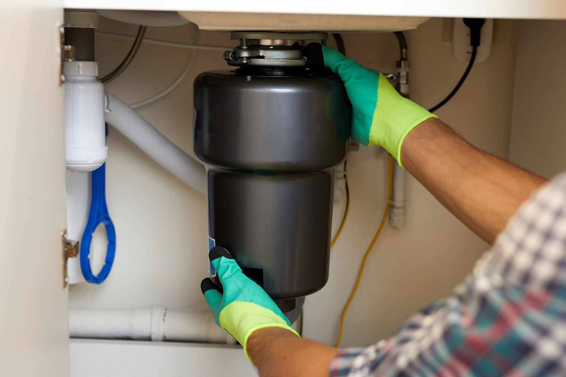 garbage-disposal-replacement - Sam's Appliance Repair Repair Technician Installing a Kitchen Garbage Disposal Unit Under the Sink For Efficient Waste Management.